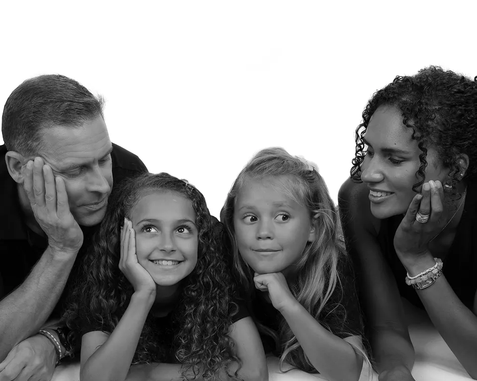 Black-and-white family group of four lying down, chins resting on their hands