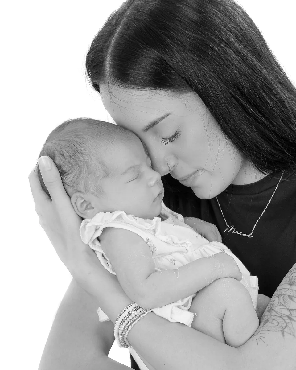 Black-and-white portrait of an adult cradling and kissing a newborn's head